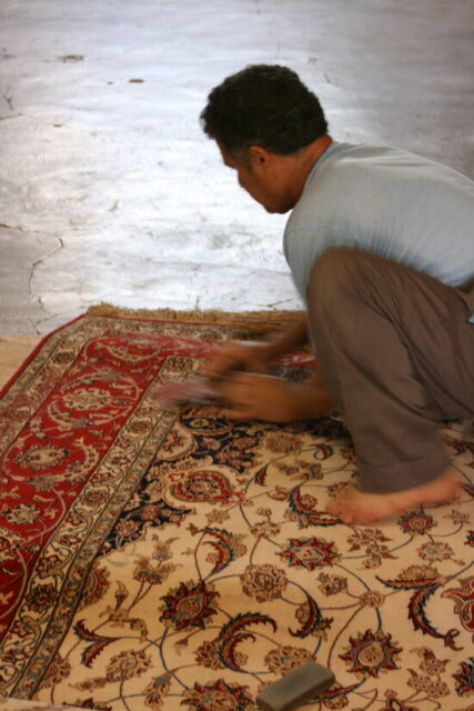 ペルシャ絨毯づくりの最後の工程で、シルクの表面を剃っている職人さん。熟達した技が求められる工程だという